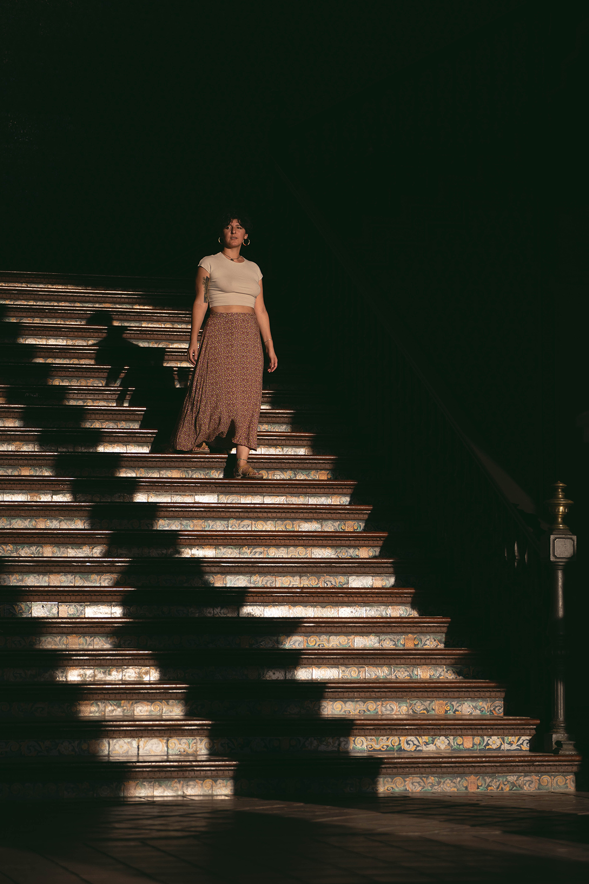  imagen de un amujer bajando unas escaleras donde le llega luz